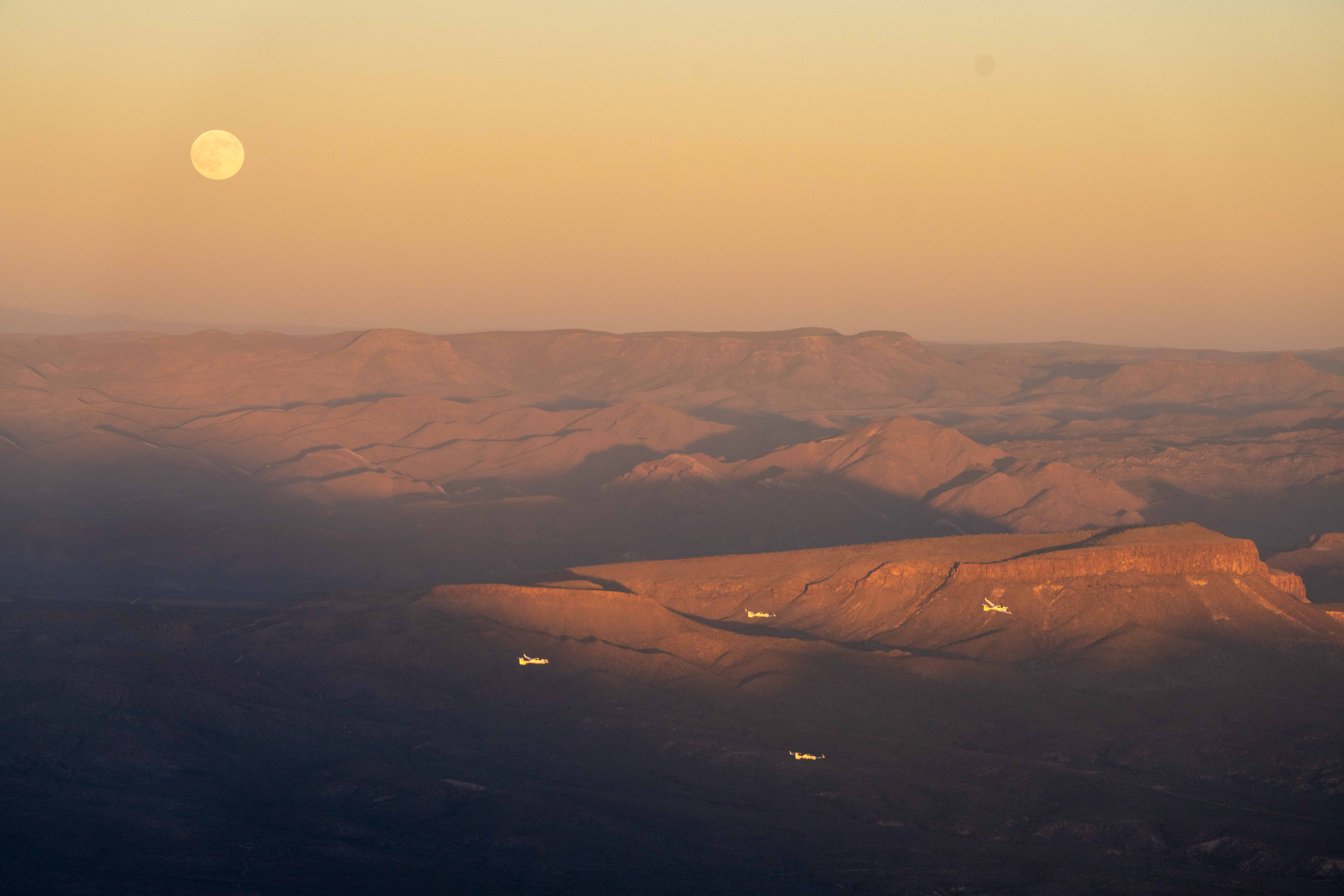 Sunset over the mountains with full moon and DA42s on approach