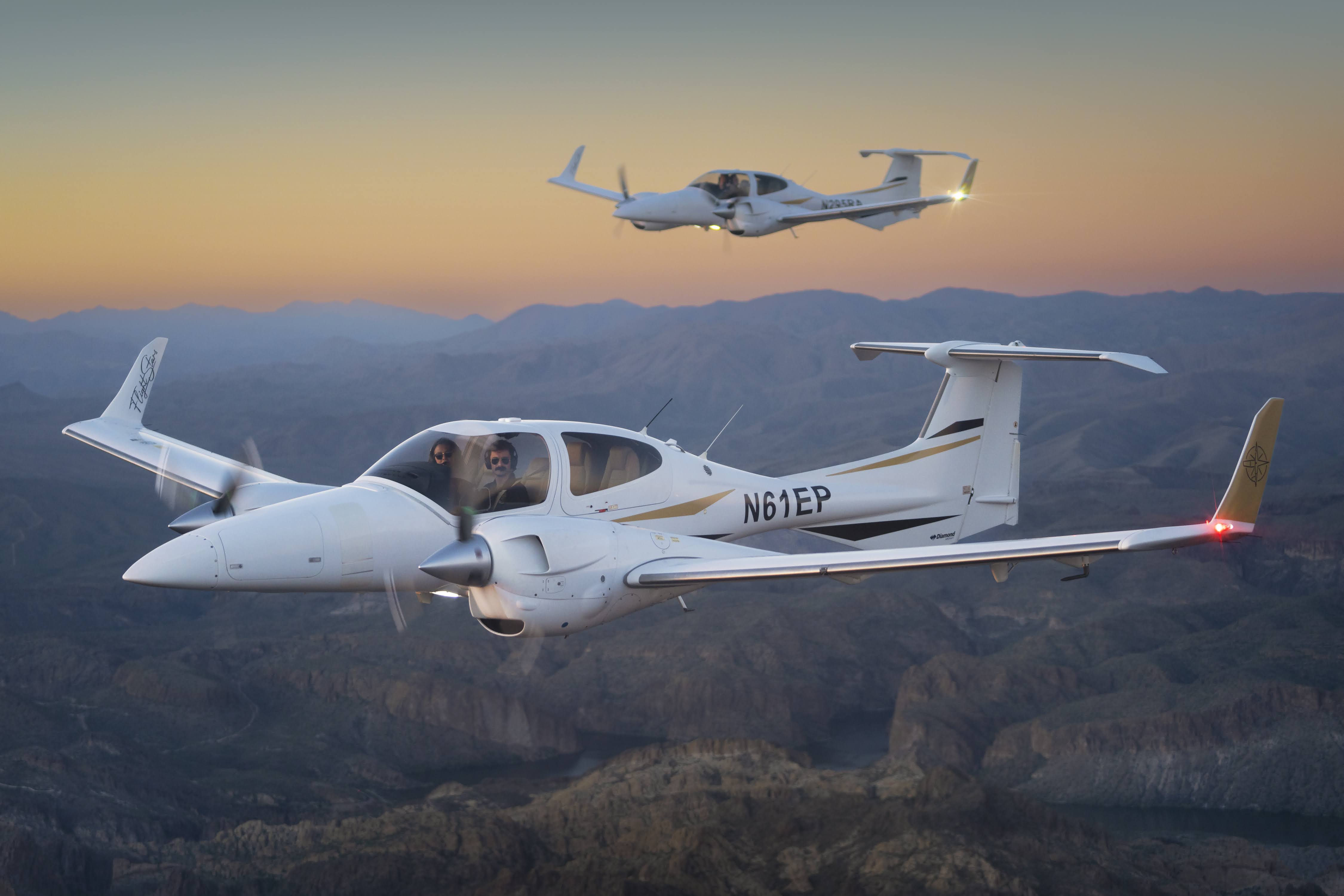 Two Diamond DA42 aircraft in formation flight at sunset